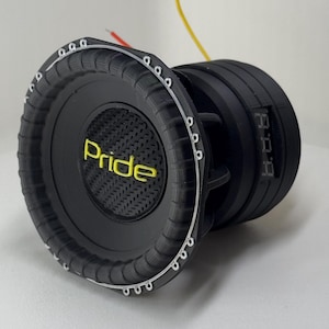 Może przedstawiać: Czarny subwoofer z napisem "Pride" w żółtych literach. Głośnik ma teksturowaną powierzchnię i szereg małych otworów wokół krawędzi. Przewody wychodzą z tyłu głośnika.