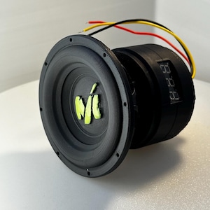 May include: A black subwoofer with a green logo and a digital display. The subwoofer has wires attached to it.