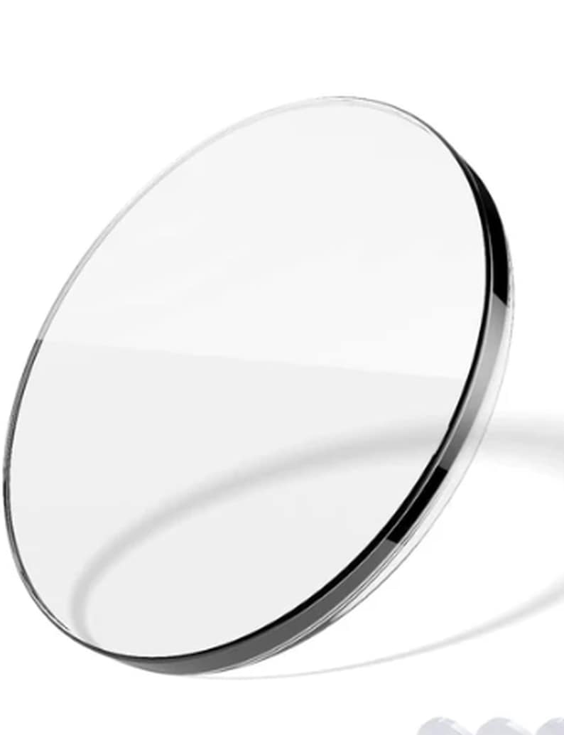 Puede incluir: Una lente circular transparente con un borde fino y oscuro. La lente es clara, permitiendo el paso de la luz. La imagen est&aacute; sobre un fondo blanco, resaltando la claridad y forma de la lente. Este producto es probablemente para gafas o equipos &oacute;pticos.