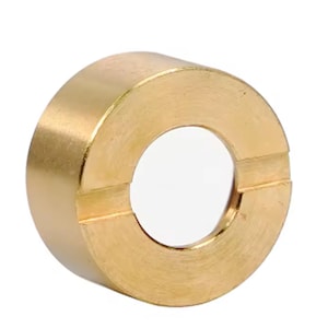 Può includere: Un anello in ottone massiccio con un'apertura circolare. L'anello ha una superficie liscia e lucida e un colore dorato caldo. L'anello è un componente hardware, probabilmente per uso industriale o meccanico.