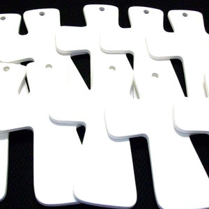 May include: A set of ten white wooden crosses with holes for hanging. The crosses are all the same size and shape, and they are arranged in a staggered pattern.