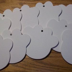 May include: Ten white paw print shaped ornaments with a hole for hanging. The ornaments are made of a smooth, white material.