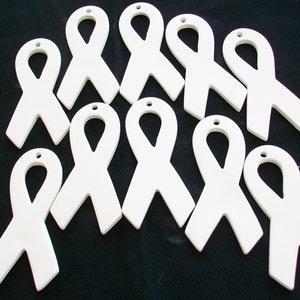 May include: Ten white ceramic ribbon ornaments, each with a hole at the top for hanging. The ribbons are all in the same shape and size, and they are all white.