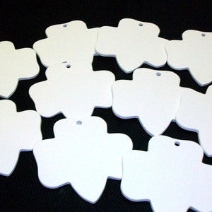 May include: Ten white, blank, unfinished, wooden, flower-shaped ornaments with a hole at the top for hanging.