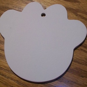 May include: White paw-shaped ornament with a hole for hanging. The ornament is made of a smooth, lightweight material.