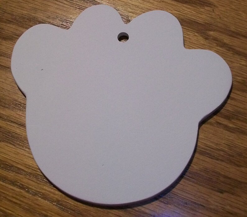 May include: White paw-shaped ornament with a hole for hanging. The ornament is made of a smooth, lightweight material.