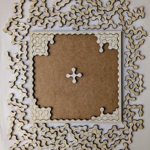 Peut inclure: Un puzzle en bois avec un fond brun et un signe plus blanc au centre. Les pièces du puzzle sont en forme de courbes irrégulières et sont dispersées autour des bords du plateau.