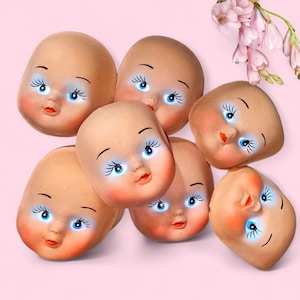 May include: Seven vintage doll heads with painted features, including blue eyes, rosy cheeks, and red lips. The doll heads are arranged on a pink background, with a sprig of pink flowers in the upper right corner.