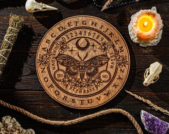 May include: A wooden planchette board with engraved letters, numbers, and a moth design. The board includes the words "YES", "NO", and "REPHRASE". The image also features a lit candle, crystals, and other mystical items.