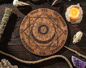 May include: A wooden Ouija board with a sun and moon design, surrounded by a circle of words including "Yes", "No", "Maybe", "Wait", "Try Again", "Rephrase", and "Unknown".