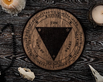 May include: A round wooden sigil with a dark triangle at the center, surrounded by text and symbols. The sigil is brown with a dark brown triangle. The image includes candles, a rosary, and a skull.
