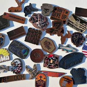 May include: A collection of various patches and emblems, featuring diverse designs and text. Notable items include an American flag, an eagle, a sunflower with the word "MAMA", and the phrase "DON'T GIVE UP".