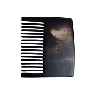 Puede incluir: Un peine negro con dientes anchos y un mango redondeado. El peine tiene el nombre de la marca "Hakiki" impreso en dorado en el mango. Diseñado para el cuidado y peinado del cabello.