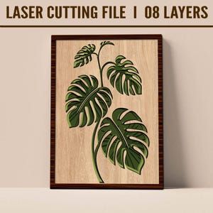Puede incluir: Obra de arte enmarcada en madera con un diseño en capas de una planta de Monstera. Las hojas verdes tienen un contorno verde oscuro, sobre un fondo claro de vetas de madera. El marco es de color marrón oscuro. El texto en la parte superior dice "LASER CUTTING FILE I 08 LAYERS".