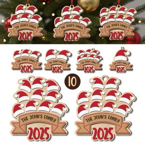 Könnte beinhalten: Weihnachtsschmuck aus Holz mit Weihnachtsmützen und dem Text "THE JOHN'S FAMILY 2025". Die Ornamente sind in verschiedenen Größen und Anordnungen, mit roten und weißen Weihnachtsmützen und einem braunen Banner.
