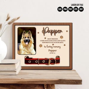 May include: A wooden memorial frame with a photo of a German Shepherd dog. The frame has a red and black dog collar with a metal buckle. The text on the frame reads "Papper, Best Friends Come Into Our Lives And Leave Pawprints On Our Hearts. In Loving Memory Papper June 12."