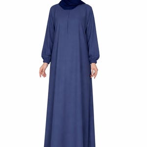 May include: A long, flowing, navy blue dress with long sleeves and a matching head covering. The dress has a simple, elegant design, with a slight A-line shape and a modest neckline. The sleeves are gathered at the wrists.