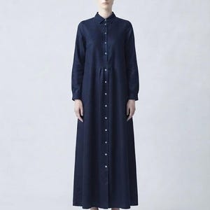 以下が含まれることがあります： 長袖、ボタン付きカフス、クラシックな襟、そして前面にフルレングスのボタン留めを備えた、床までの長さのネイビーブルーのシャツドレス。この衣服は、ウエストの縫い目があるフィットしたボディスと、足首までの長さの流れるようなスカートが特徴です。
