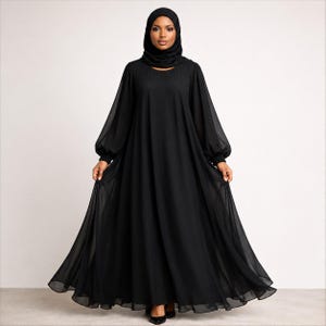 May include: A floor-length black abaya dress featuring long, loose, sheer chiffon sleeves with gathered cuffs and a round neckline. The garment is constructed from a flowing, opaque black fabric that drapes fully to the floor, paired with a matching black hijab.