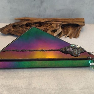 May include: A triangular iridescent glass box with a green base. The box is decorated with a cluster of iridescent stones and a dangling crystal.