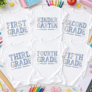 Peut inclure: Six t-shirts blancs à manches courtes avec du texte à motifs floraux et à carreaux bleus. Les chemises affichent les niveaux First Grade, Kindergarten, Second Grade, Third Grade, Fourth Grade et Fifth Grade, avec le nom miss anna en dessous.