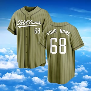 Puede incluir: Una camiseta de b&eacute;isbol verde oliva con rayas verticales oscuras, frente abotonado y mangas cortas. El frente presenta el texto Add Name y el n&uacute;mero 68. La parte posterior muestra el texto YOUR NAME sobre el n&uacute;mero 68 grande en blanco.