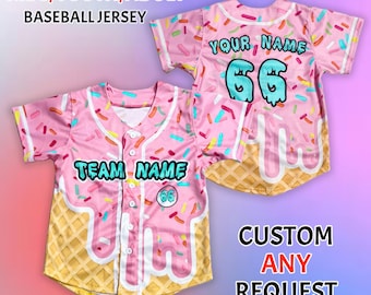 Puede incluir: Camiseta de béisbol rosa con un patrón de chispas de colores, un diseño de cono de gofre y el texto "TEAM NAME" y "YOUR NAME". Disponible en tallas para jóvenes y adultos.