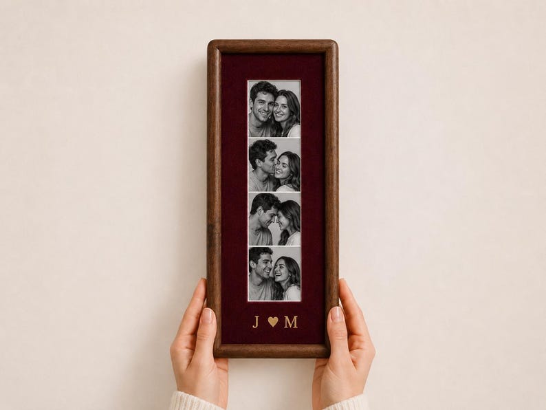 May include: A rectangular dark wood picture frame featuring a deep burgundy velvet mat. The frame displays a vertical strip of four black and white photographs of a couple. Below the photos, the gold letters J and M are separated by a heart.
