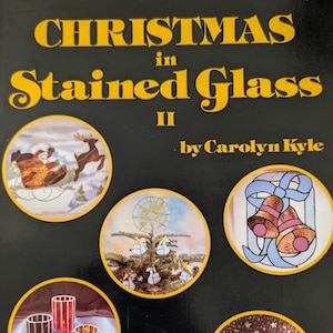 May include: A book cover titled Christmas in Stained Glass II by Carolyn Kyle. The black cover features yellow text and four circular illustrations depicting a sleigh with a reindeer, a star above a tree, two bells with a bow, and candle holders.