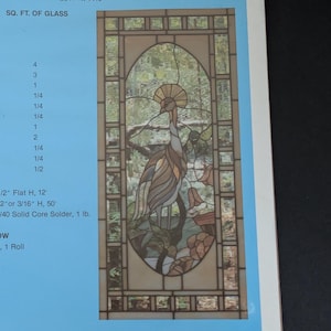 May include: A rectangular stained glass panel featuring an oval center design of a crested bird standing among stylized flowers and foliage. The panel is framed by a geometric border of clear glass squares and rectangles, set against a light blue background.
