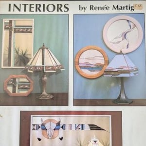 May include: A promotional display titled INTERIORS by Renée Martig featuring two table lamps with geometric shades, two rectangular mirrors, two circular wall art pieces, and a large horizontal print depicting a steer skull with geometric patterns.