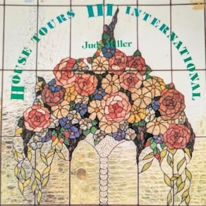 May include: A stained glass panel featuring a vibrant floral bouquet with red, orange, yellow, and blue flowers. The text HOUSE TOURS III INTERNATIONAL by Judy Miller is printed in green across the top. The design includes trailing green leaves.