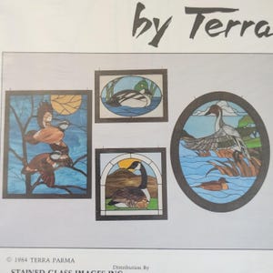 May include: A collection of four stained glass panels featuring waterfowl designs, including ducks and geese in various settings. The panels are framed in dark wood and display scenes with blue water, trees, and suns. Text reads by Terra and 1984 Terra Parma.
