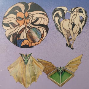 May include: A collection of four stained glass art pieces featuring a bearded wizard holding a sphere, a white unicorn with a flowing mane, a green dragon head with large wings, and a green dragon head emerging from a rectangular box.