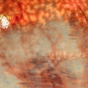 May include: A sheet of textured glass featuring a vibrant gradient of deep orange and fiery red at the top, transitioning into a translucent, pale cream and light beige base with subtle, swirling patterns and a distinct, bright white light reflection.