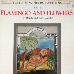 May include: A pattern book titled FULL-SIZE WINDOW PATTERNS SET 2 FLAMINGO AND FLOWERS by Randy and Judy Wardell. The cover features a stained glass illustration of a pink flamingo, a palm tree, mountains, and a blue sky within a gray frame.