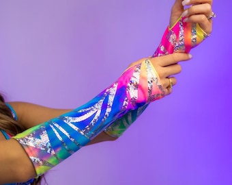 May include: Colorful arm sleeves with a vibrant rainbow gradient and silver accents. The sleeves feature a geometric pattern and are designed to be worn on the arms. The sleeves are a mix of pink, yellow, blue, and green.