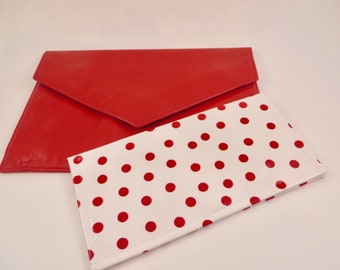 May include: A red leather clutch with a white and red polka dot envelope style clutch.