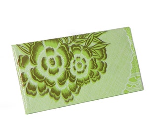 May include: A green and brown floral patterned wallet with a white lace trim.