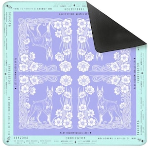 May include: A rectangular mousepad with a light purple background featuring a repeating pattern of white flowers, Doberman Pinschers, and text. The mousepad has a black rubber backing and a light blue border with text.