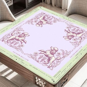 May include: A square table with a light purple surface featuring illustrations of poodles and floral elements. The table's border is light green with text. The table is made of wood and has decorative cutouts on the sides.