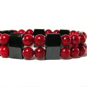 May include: A red and black beaded bracelet with square black beads alternating with round red beads.
