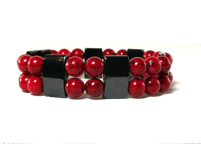 May include: A red and black beaded bracelet with square black beads alternating with round red beads.