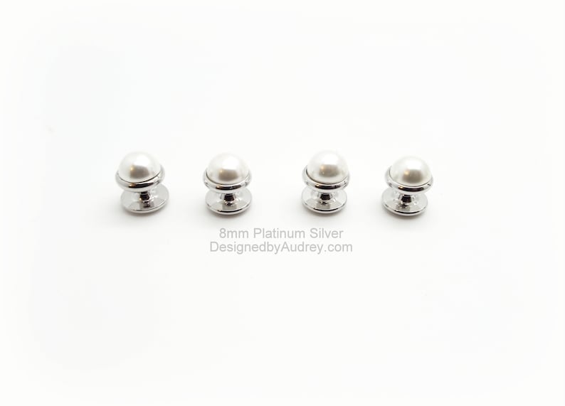 May include: Four 8mm pearl buttons with a platinum silver finish. The buttons are round and have a raised pearl centre. The buttons are arranged in a row on a white background.