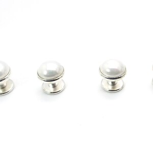 May include: Four white pearl cabinet knobs with silver bases.