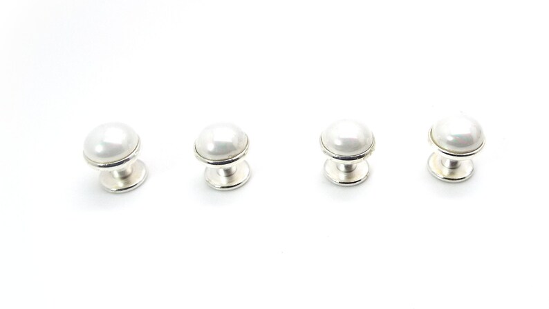 May include: Four white pearl cabinet knobs with silver bases.