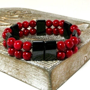 May include: A double-strand bracelet with red beads and black rectangular beads.