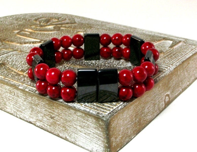 May include: A double-strand bracelet with red beads and black rectangular beads.