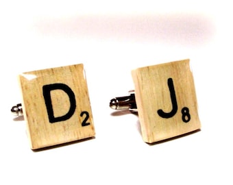 May include: A pair of cufflinks made from wooden Scrabble tiles. The left cufflink features the letter "D" with the number "2" below it. The right cufflink features the letter "J" with the number "8" below it.