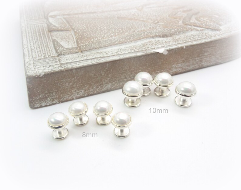 May include: A set of pearl buttons in two sizes, 8mm and 10mm. The buttons are white and have a silver base.
